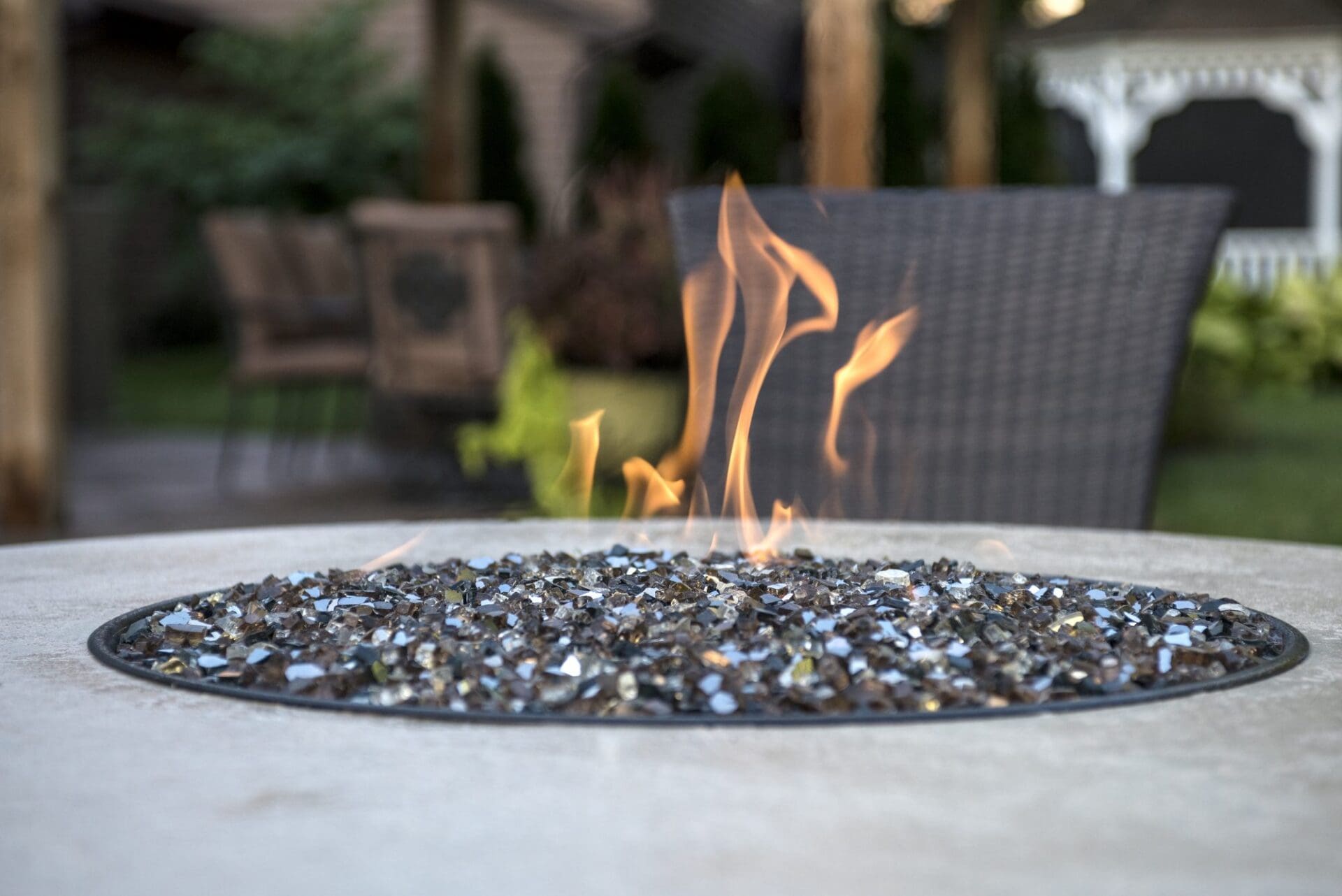 Round gas fire pit with fire-glass set into a paver patio — Apex Landscaping