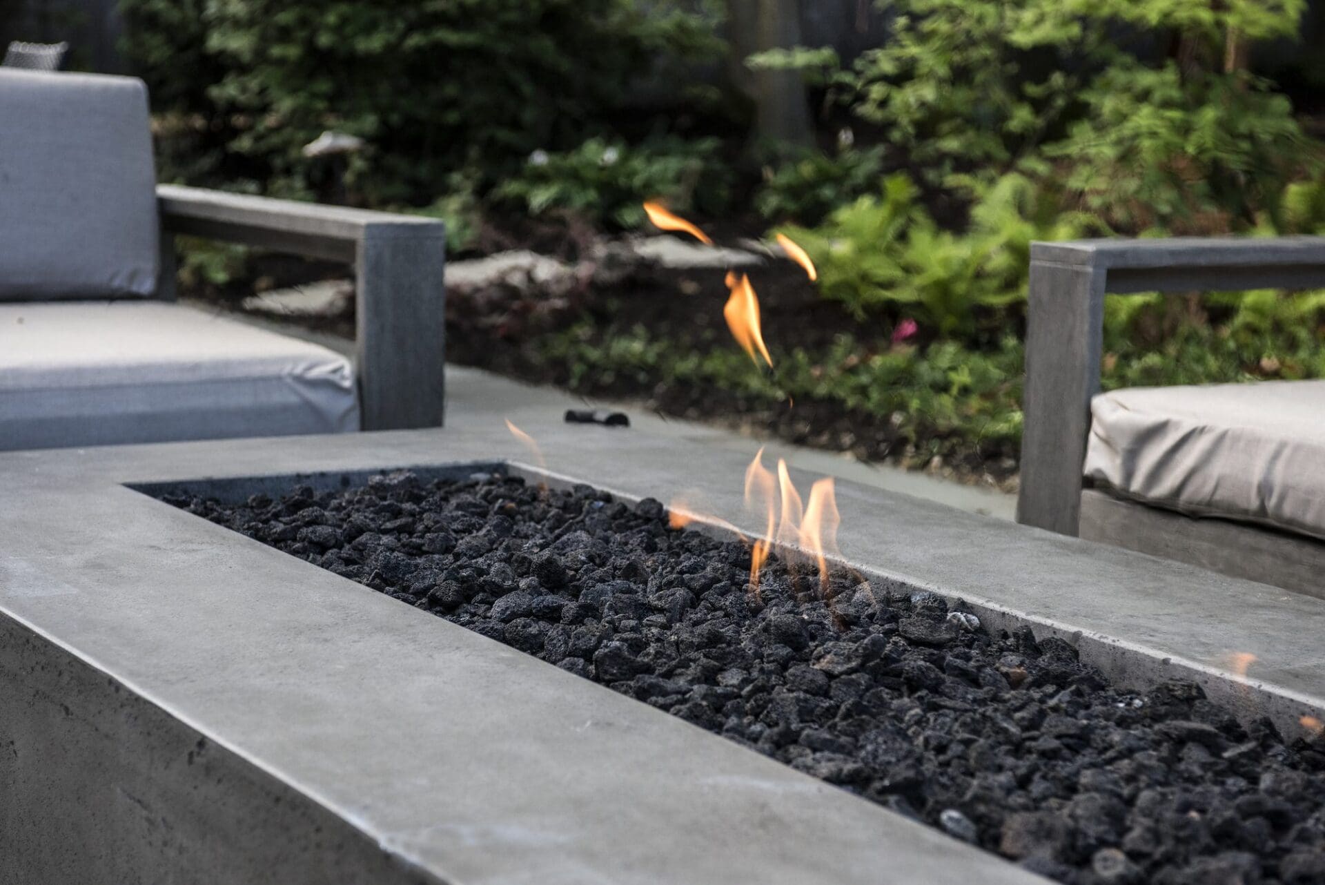 Modern linear gas fire feature with lava rock on a patio — Apex Landscaping