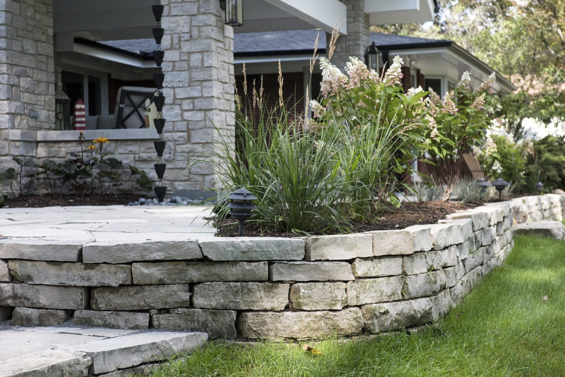 Natural stone retaining wall with layered plantings — Apex Landscaping