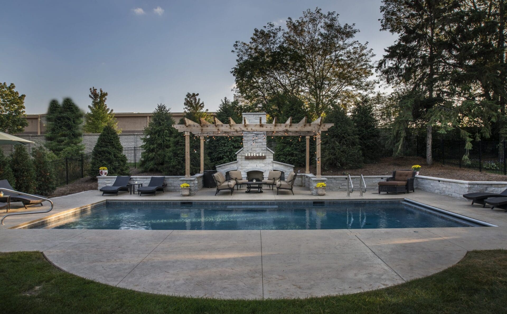 Pool with a pergola and outdoor fireplace — Apex Landscaping