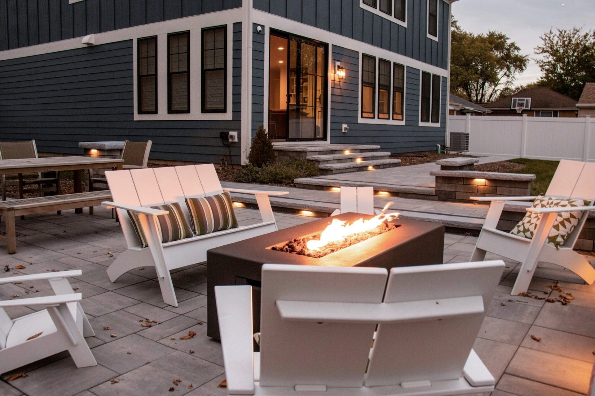 Fire table with Adirondack chairs and string lights — Apex Landscaping