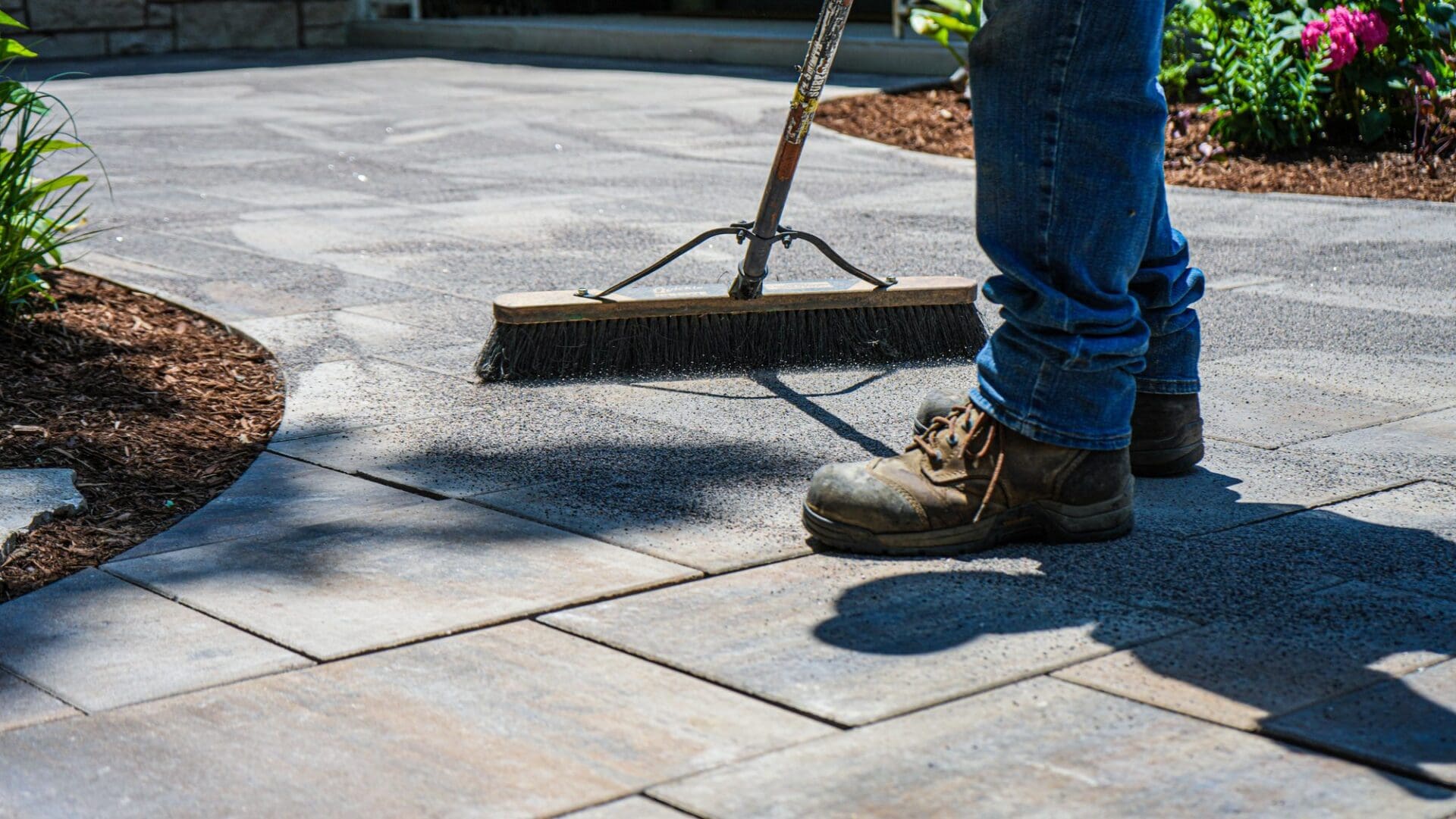 Sweeping polymeric sand to finish a paver walkway — Apex Landscaping