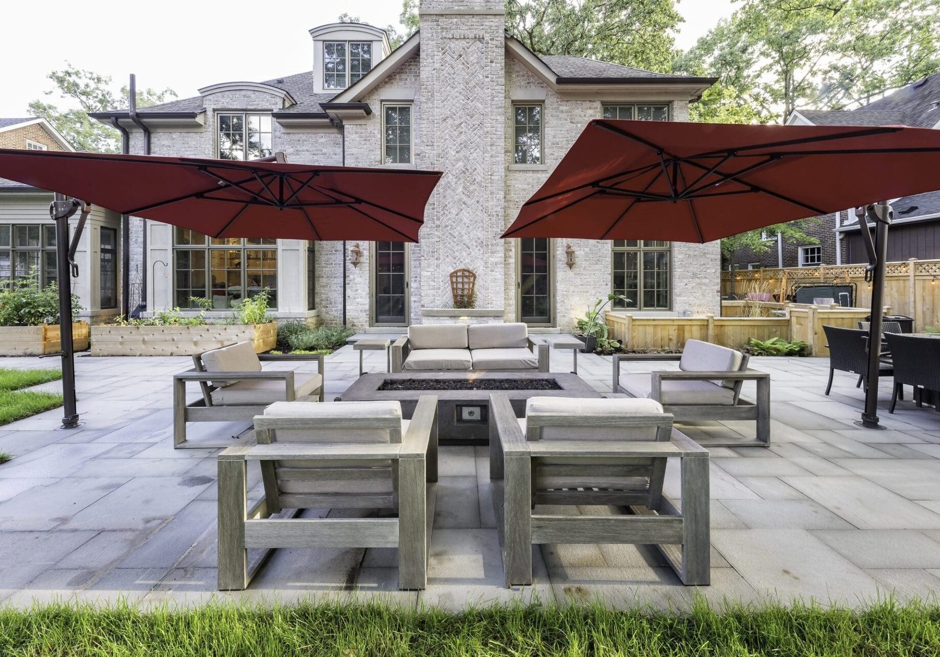 Paver patio with market umbrellas and a fire table — Apex Landscaping