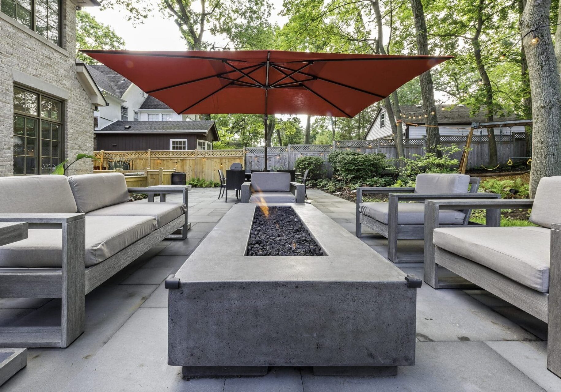Modern linear fire feature with a patio sectional — Apex Landscaping design-build