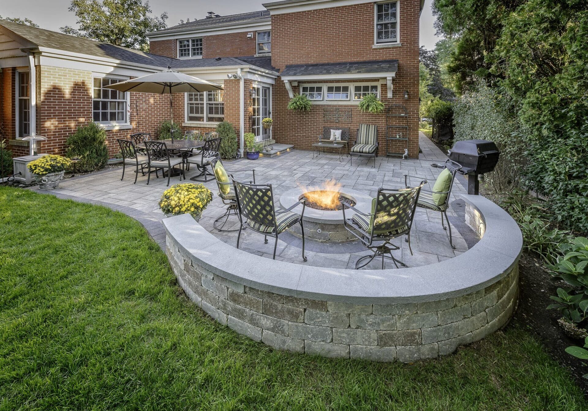 Curved paver seating wall around a fire pit — Apex Landscaping design-build